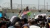 FILE - U.S. soldier holds a 'Gate Closed' sign as hundreds of people gather near an evacuation checkpoint on the perimeter of Hamid Karzai International Airport, in Kabul, Afghanistan, Aug. 26, 2021.