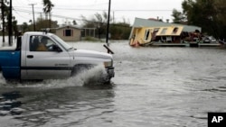 德克萨斯遭受飓风“哈维”侵袭地区积水严重，一辆卡车在积水中驶过一幢受损严重的房子（2017年8月26日） 