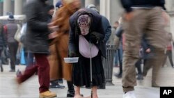 Seorang perempuan mengemis di antara orang lewat di jalanan kota Milan (Januari 2013). Ekonomi zona Euro masih lemah dan pengangguran terus meningkat. 