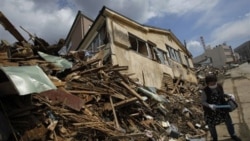 An earthquake survivor searches for belongings in her destroyed house in the city of Kesennuma in northern Japan