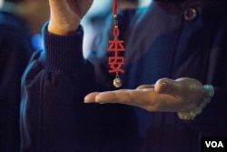 台北第二殡仪馆内的慈济义工在现场分发“平安”挂饰。（美国之音记者方正拍摄）