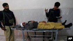 파키스탄 군인들이 무장 괴한의 총격을 받고 중상을 입은 동료의 옆을 지키고 있다.