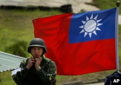 资料照：台湾旗帜前一名士兵整理自己的头盔。