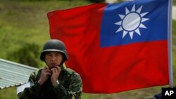 资料照：台湾旗帜前一名士兵整理自己的头盔。 