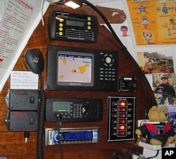 The control panel inside the cabin showing [top, clockwise]: a battery monitor, cart plotter, bilge pump switch panel, stereo, VHF radio and Sea-Me control switches