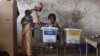 A woman carrying a baby on her back votes at a polling station in Freetown on November 17, 2012.