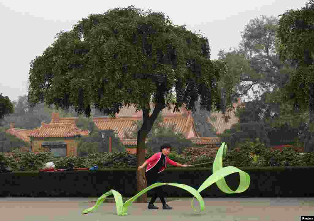Seorang perempuan berolahraga dengan menggunakan pita pada suatu pagi di Taman Jingshan, Beijing, China.