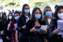 Students wear face masks as a precaution against COVID-19, as they line up to undergo an aptitude test to access the University of Medicine, in Rome, Italy, Sept. 3, 2020.