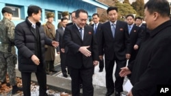 朝鲜首席代表、和平统一委员会主席李善权（中）在板门店非军事区走过边界时与迎接他的韩国官员握手（2018年1月9日）