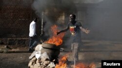 布隆迪首都布琼布巴街头一名抗议者站在燃烧的路障前（2015年5月14日）