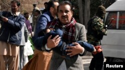 巴基斯坦奎达市一教堂遭武装分子袭击，图为一名男子抱着一个男孩逃出。（2017年12月17日）