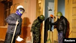 Demonstran anti-pemerintah Ukraina berdiri di depan pintu masik kantor Kementerian Kehakiman di pusat kota Kyiv (27/1).