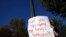 A protester holds a sign outside the U.S. Supreme Court building, as the court justices engage in arguments over the fate of Obamacare laws, in Washington, Nov. 10, 2020.