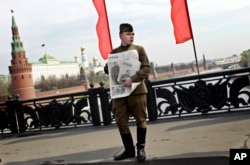 共产党支持者穿着第二次世界大战时的苏联红军军服，抱着印有斯大林像的苏共喉舌《真理报》，在莫斯科的五一节集会中（2010年5月1日）