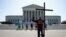 Tom Alexander holds a cross as he prays prior to rulings outside the Supreme Court on Capitol Hill in Washington, July 8, 2020.