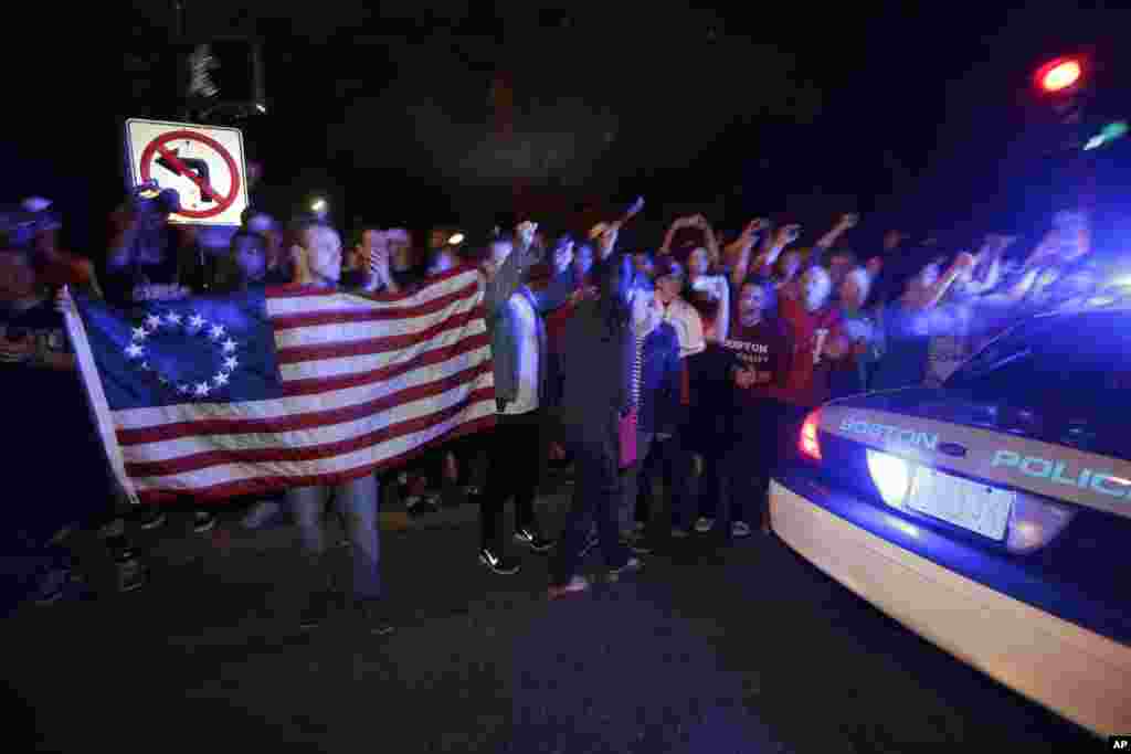 A police cruiser drives by as people react to news of the arrest of one of the Boston Marathon bombing suspects, April 19, 2013, in Boston.
