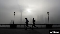 FILE - People jog past the Pudong Financial District shrouded in fog and pollution at the Shanghai Bund in Shanghai, China, Thursday, April 14, 2016. Air pollution has caused 5.5 million premature deaths globally in 2013, outpacing disease, a new study has found.