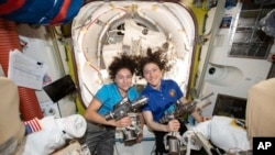In this photo released by NASA, U.S. astronauts Jessica Meir, left, and Christina Koch pose for a photo in the International Space Station, Oct. 17, 2019. 