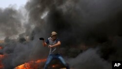 一名巴勒斯坦抗议者在加沙跟以色列的边界地带向以色列部队投掷石块(2018年4月20日)