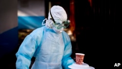 Seorang petugas medis mengenakan baju pelindung membawa makanan ke ruang isolasi untuk pasien yang membawa virus Marburg di Rumah Sakit Nasional Kenya di Nairobi, Kenya, 8 Oktober 2014. (Foto: Ben Curtis/AP Photo)