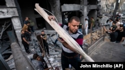 Wakazi wa Gaza wakikusanya baadhi ya mali zao kutoka vifusi vya jengo la Al-Jawhara lililobomolewa na makombora ya Israel