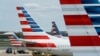 FILE - A member of a ground crew walks past American Airlines planes parked at the gate during the coronavirus outbreak at Ronald Reagan National Airport in Washington, April 5, 2020.