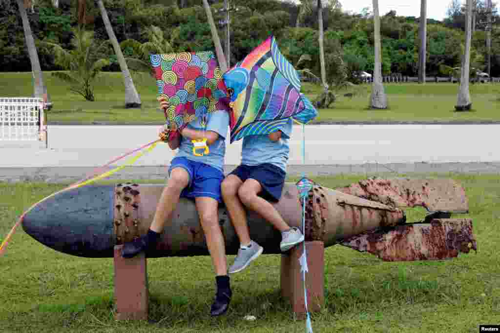 美国太平洋岛屿关岛的亚桑纪念公园，小学生们坐在第二次世界大战的鱼雷上。估计炸药已经掏空（2017年8月11日）。人类最早在大约4000年前定居关岛，他们是查莫罗人的祖先。查莫罗人是关岛人数最多的族群。关岛最大城市为德德多，主要语言为英语和查莫罗语。