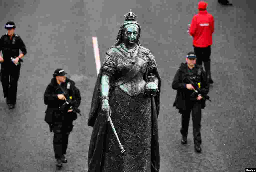 2018年10月12日，在英国温莎城堡，在英国公主尤金妮的皇室婚礼之前，武装警察在维多利亚女王雕像下面行进。