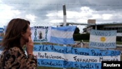 FILE - A woman looks at signs in support of the 44 crew members of the ARA San Juan submarine missing at sea, which are placed on a fence outside the Argentine Naval Base where the submarine sailed from, in Mar del Plata, Argentina, Nov. 20, 2017.