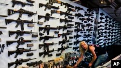 资料照 - 摄于2014年7月20日美国科罗拉多州的一家枪支售卖店。店内的一位女工作人员正在按客户的要求挑选枪支。