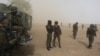 Cameroonian soldiers stand guard amidst dust kicked up by a helicopter in Kolofata, March 16, 2016. Hit hard by Boko Haram, Benin, Cameroon, Chad, Niger, and Nigeria have put together a regional force to try to wipe out the militant group.