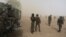 Cameroonian soldiers stand guard amidst dust kicked up by a helicopter in Kolofata, March 16, 2016. Hit hard by Boko Haram, Benin, Cameroon, Chad, Niger, and Nigeria have put together a regional force to try to wipe out the militant group.