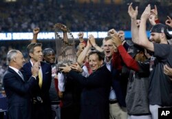 El presidente de los Medias Rojas de Boston, Tom Werner, sostiene el trofeo del campeonato mientras el presidente Sam Kennedy, tercero desde la derecha, el gerente Alex Cora, segundo desde la derecha y el lanzador Chris Sale, derecha, celebran después del Juego 5 de la Serie Mundial de béisbol contra los Dodgers de Los Angeles. Octubre 28 de 2018. AP
