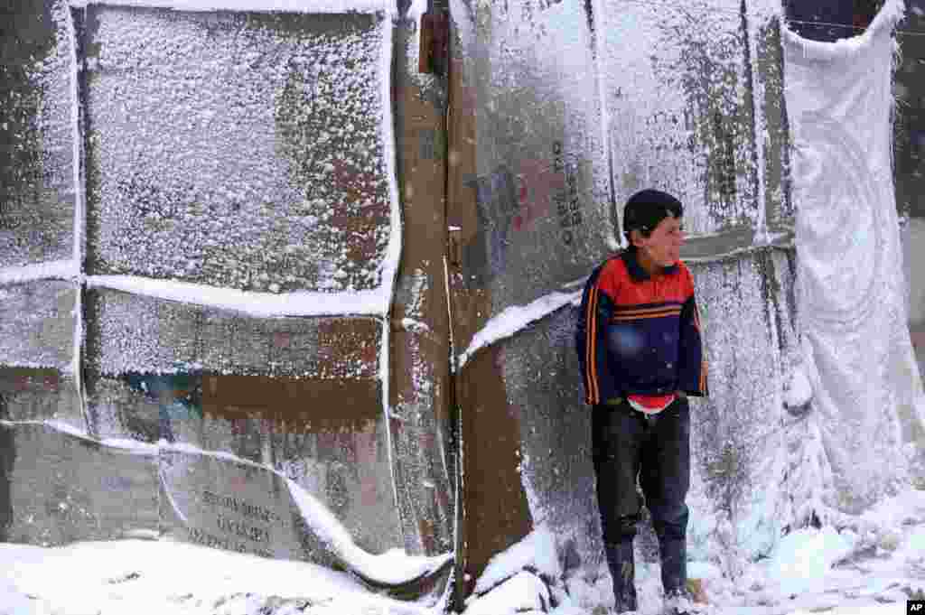 Seorang bocah Suriah berdiri di tengah salju di luar tenda tempat tinggalnya di kamp pengungsi lembah Bekaa, Lebanon timur, saat badai salju mulai menghantam wilayah tersebut (11/12). 