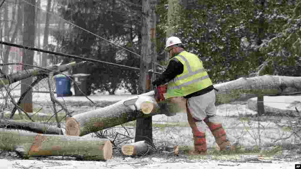 Un travailleur de Duke Energy, compagnie électrique, utilise une tronçonneuse pour couper un arbre tombé sur des lignes électriques à Matthews, Caroline du Nord, 22 janvier 2016.
