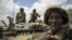  In this photo released by the African Union-UN Information Support Team, Kenyan soldiers with the African Union Mission in Somalia sit on top of an armored vehicle in Saa'moja, north-west of the port city of Kismayo, October 1, 2012. 