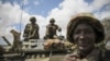  In this photo released by the African Union-UN Information Support Team, Kenyan soldiers with the African Union Mission in Somalia sit on top of an armored vehicle in Saa'moja, north-west of the port city of Kismayo, October 1, 2012. 