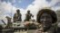  In this photo released by the African Union-UN Information Support Team, Kenyan soldiers with the African Union Mission in Somalia sit on top of an armored vehicle in Saa'moja, north-west of the port city of Kismayo, October 1, 2012. 