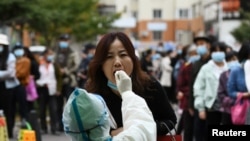 中国青岛的医护人员正在给一名妇女做核酸检测。（2020年10月13日）