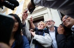 Britain's Labour Party leader and Prime Minister Boris Johnson's rival in the country's upcoming election Jeremy Corbyn takes pictures with people outside the University of London, in London, Britain, Dec. 3, 2019.