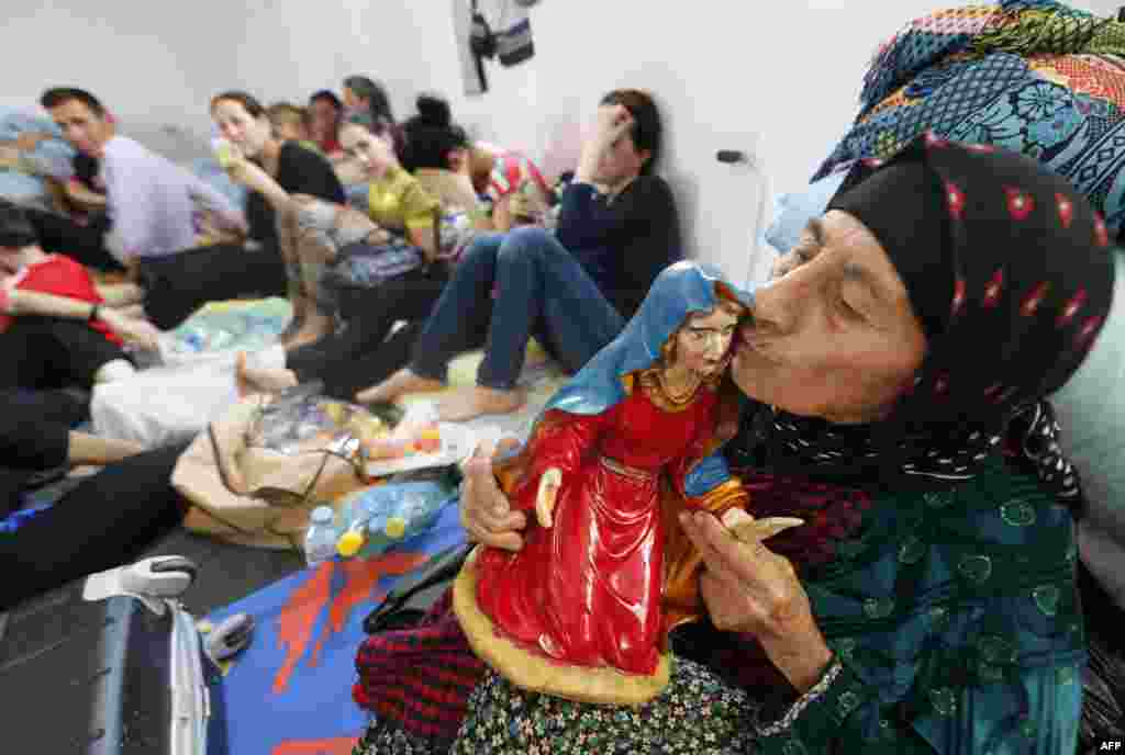 Seorang perempuan Kristen Irak yang melarikan diri dari kekerasan di desa Qaraqush dan Bartala mencium patung yang menggambarkan orang suci umat Kristen di pusat komunitas di kota Arbil Kurdi di daerah otonomi Kurdistan, Irak.&nbsp; &nbsp; 