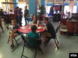 A family eats lunch and participates in the Caribbean Marketplace Trivia game in Little Haiti, Miami, Florida. (Photo: S. Lemaire / VOA)