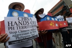 FILE - Filipino students hold replicas of Chinese maritime surveillance ships as they shout anti-Chinese slogans during a rally near Malacanang Palace in Manila, March 3, 2016.