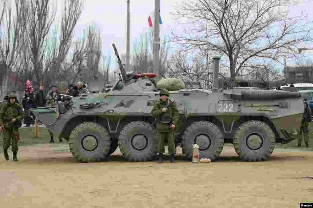 Military personnel stand next to an armored personnel carrier (APC) in the Crimean port city of Feodosiya, Ukraine, March 2, 2014.