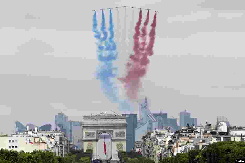 Sembilan jet alpha milik Angkatan Udara Perancis melepaskan asap dengan warna-warna nasional saat terbang di atas Arc de Triomphe dan Champs-Elysees selama parade militer Hari Bastille di Paris (14/7).&nbsp;(Reuters/Thomas Samson)