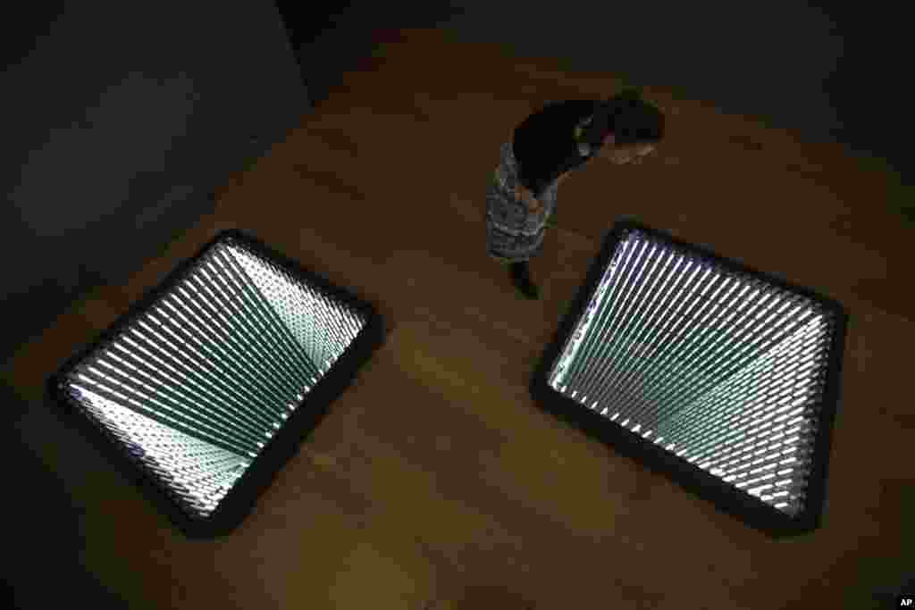 បុគ្គលិក​ម្នាក់​ឈរ​ថត​រូប​នៅពេល​ដែល​នាង​កំពុង​មើល​ប្រអប់​ភ្លើង​និង​កញ្ចក់​ដែល​បង្កើត​ឡើង​ដោយ​សិល្បករ​ Ivan Navarro ជនជាតិ​ឈីលី​​ &laquo;The Twin Towers&raquo; អំឡុង​ការ​តាំង​ពិព័រណ៌​សិល្ប &laquo;យុគសម័យ​ភេរវកម្ម: សិល្ប 9/11&raquo; នៅសារមន្ទីរសង្រ្គាម​ក្នុង​ទីក្រុង​ឡុងដ៏។