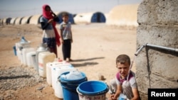 A displaced Iraqi boy fills a bottle with water in Jada camp south of Mosul, Iraq Aug. 9, 2017.