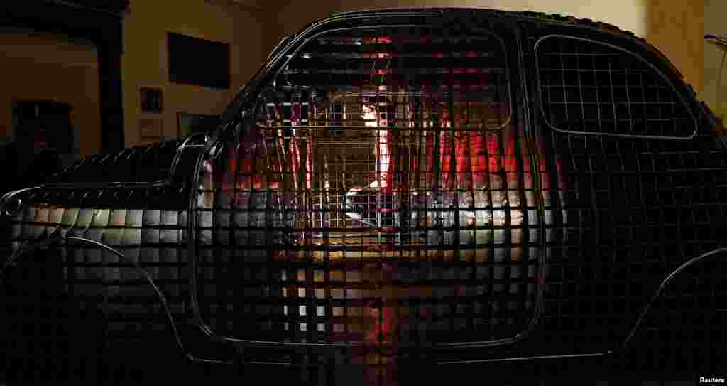 Seorang karyawan galeri seni, berpose di belakang patung artis Ron Arad, di Royal Academy of Arts di pusat kota London, Inggris.