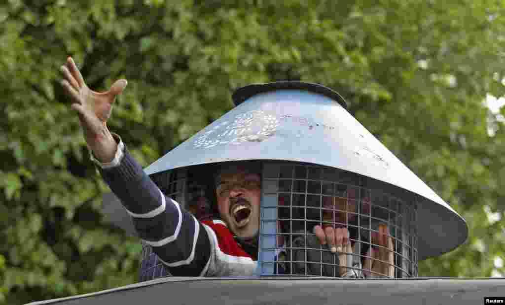 Seorang pegawai pemerintah meneriakkan slogan dari dalam kendaraan polisi setelah ia ditahan ketika melakukan protes menuntut kenaikan gaji di Srinagar, Kashmir-India.