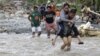 Residents cross a river in the flash flood-hit village of Andap, New Bataan township, Compostela Valley in southern Philippines Dec. 5, 2012. 